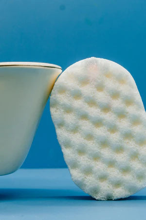 white sponge leaning against a cup in a blue background